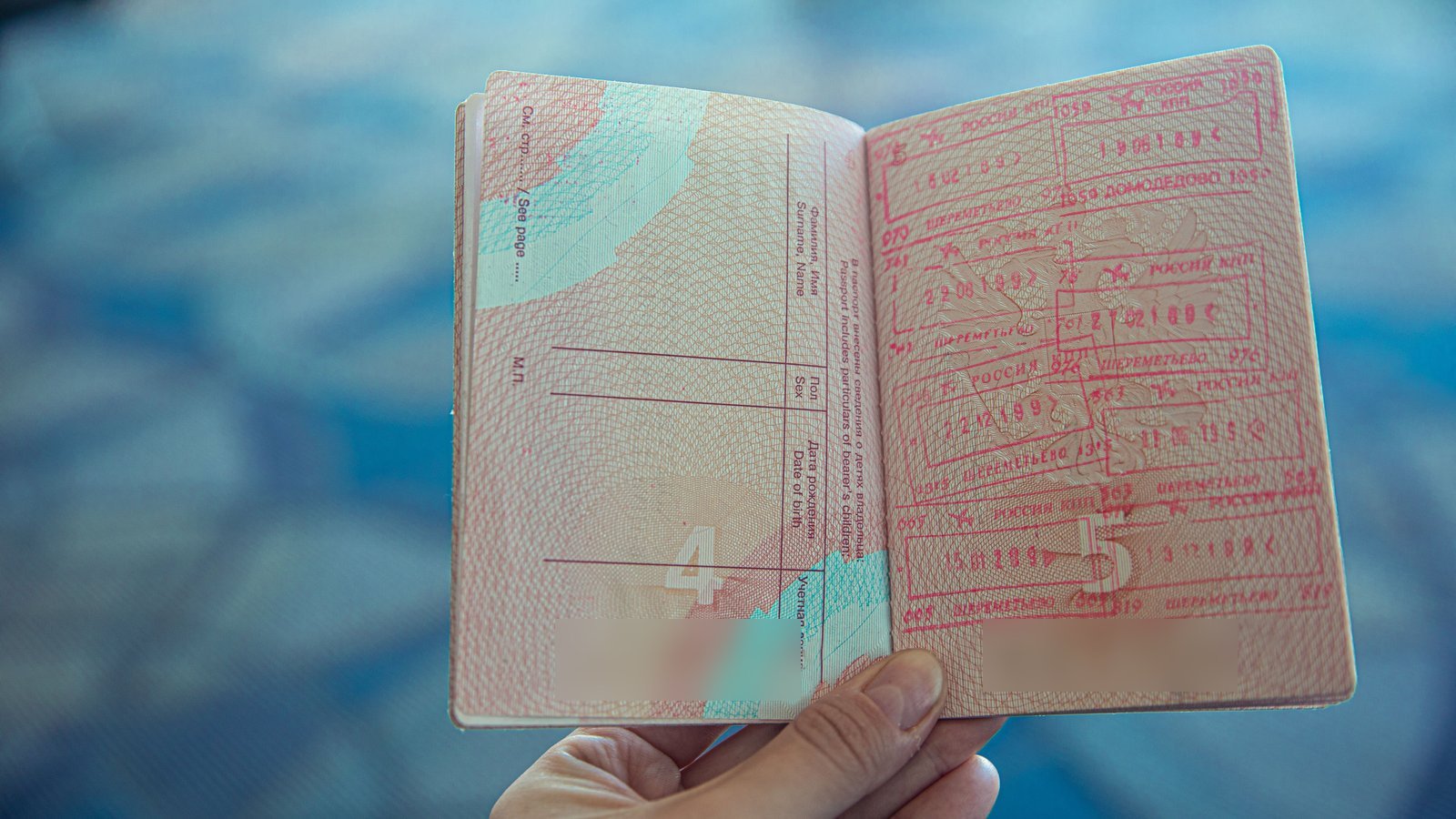 A traveller holds open a passport filled with entry and exit stamps