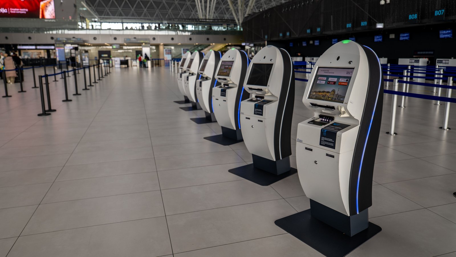 A row of self-service kiosks in an airport departure hall